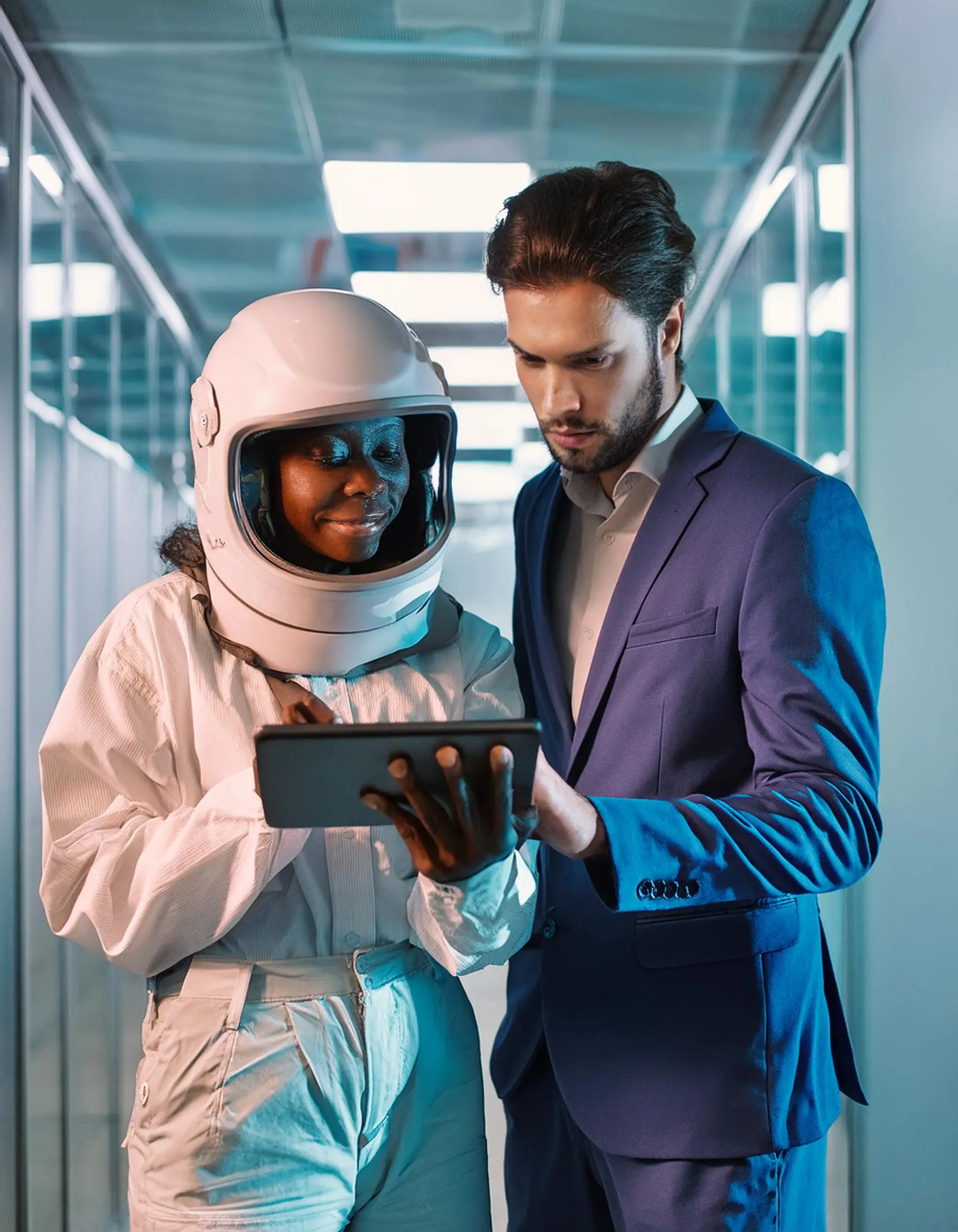 image d'une femme souriante astronaute en combinaison qui regarde la tablette d'un homme en constume